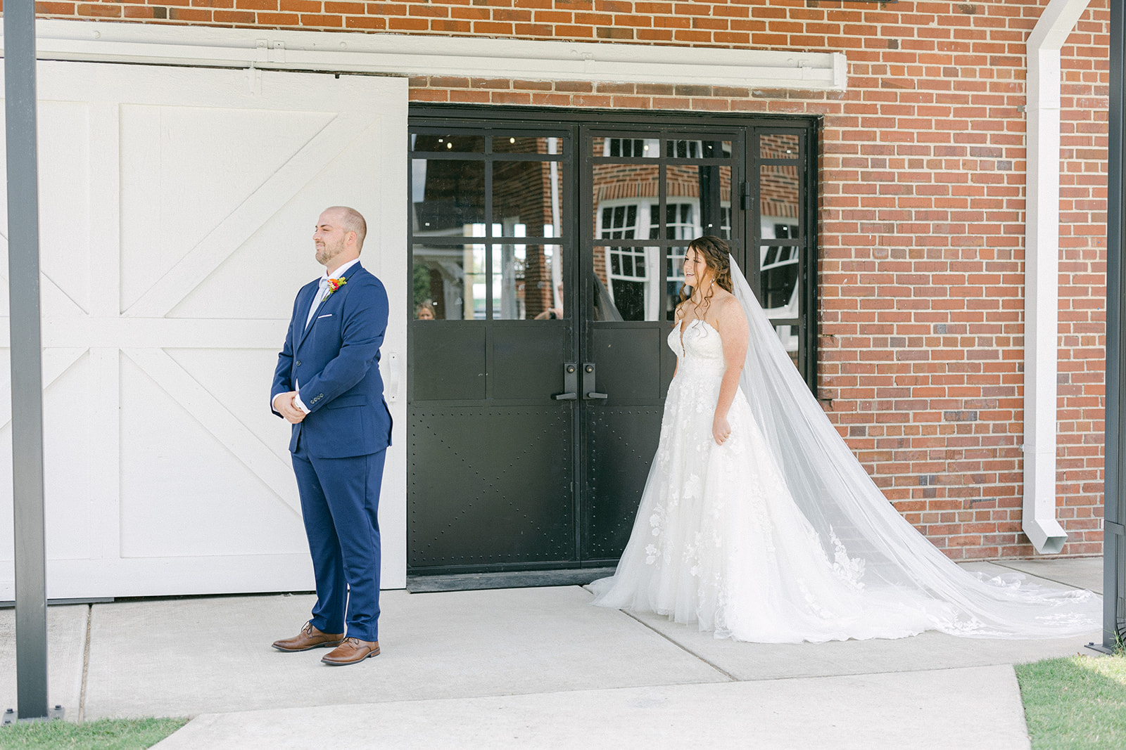 Bride standing behind groom for first glance photos at The Chair Factory
