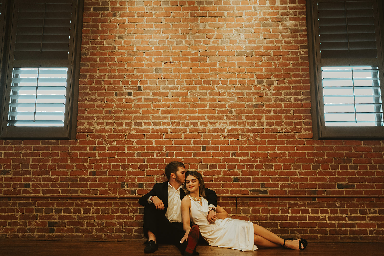 Bride and groom posing on the floor in front of a brick wall in north georgia