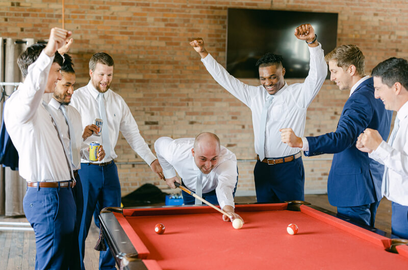 Groomsmen playing pool in groom's loft in Gainesville industrial wedding venue
