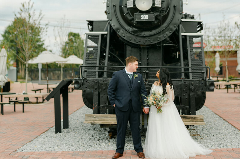 Bride and groom posing in front of vintage train in Gainesville

